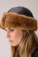 Gorro de invierno combinado de cuero negro con textura rugosa y detalle de piel sintética marrón en el borde inferior.