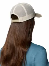 Gorro tipo trucker Columbia Mesh Snap Back de color beige, con visera curva en tono tostado, paneles traseros de malla transpirable y un parche frontal bordado con diseño de montañas y el logotipo de la marca.