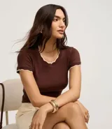 Top de manga corta ajustado al cuerpo, color marrón oscuro, con cuello redondo y bordes festoneados en color crema o beige claro.