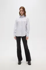 Camisa de algodón a rayas verticales, con cuello camisero, cierre frontal de botones y detalle de strass aplicado en la parte superior delantera.