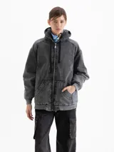 Campera estilo bomber de denim lavado color gris oscuro, con cierre frontal, capucha con interior de corderito y bolsillos frontales tipo canguro.