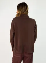 Sweater de punto color marrón chocolate, con cuello alto y puños y ruedo acanalados. Presenta un diseño holgado y mangas largas.
