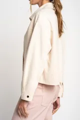 Camisa tipo sobrecamisa oversize color crudo, confeccionada en tejido de gamuza vegana con cierre frontal de botones metálicos y cuello clásico.