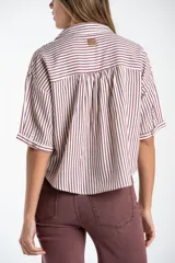 Camisa de corte oversize con estampado de rayas verticales, cuello clásico y mangas cortas. Presenta cierre frontal con botones y un diseño fluido y ligero.