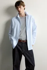 Camisa slim fit de algodón color celeste con sutil patrón de cuadros, cuello clásico y manga larga con puños abotonados.