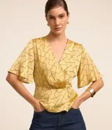 Blusa de mangas cortas con escote V traspasado, pliegues y recorte en la cintura. Confeccionada en tejido con efecto satinado y estampado geométrico con líneas curvas.