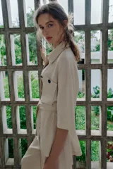Chaqueta de estilo safari confeccionada en mezcla de lino, color azul marino, con cuello solapa, mangas cortas y cierre frontal con botones ocultos. Presenta bolsillos de parche en el pecho con solapa y botones, además de un cinturón ajustable del mismo tejido para anudar en la cintura.