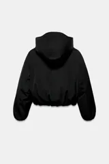 Chaqueta acolchada de corte corto con cuello subido y capucha. Presenta cierre frontal con cremallera termosellada y solapa con botones a presión, bolsillos laterales con cierre, mangas largas con puños elásticos y bajo ajustable con cordones.