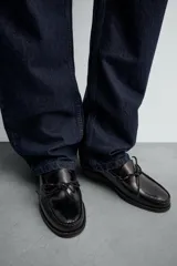 Mocasín de vestir fabricado en piel con acabado brillante, presenta un detalle de lazo en el empeine y suela a contraste con ligero tacón.