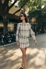 Falda pantalón de tiro alto confeccionada en tejido de tweed con estampado a cuadros en tonos beige, azul y negro. Presenta detalles de falsos botones y cierre lateral con cremallera oculta.