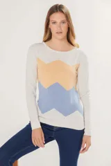 Buzo tejido de punto con diseño de bloques en zigzag en tonos beige, naranja y celeste, de cuello redondo y manga larga.