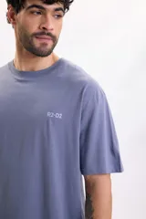 Remera oversize de manga corta en color azul piedra, con estampa en la espalda del personaje R2-D2 de Star Wars en tonos celestes.
