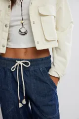 Jean azul de tiro medio con cintura elástica ajustable mediante cordón, bolsillos plaqué delanteros y diseño de pernera ancha y holgada.
