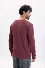 Remera manga larga de tejido texturizado tipo wafle en color bordó, con cuello redondo y puños elásticos.