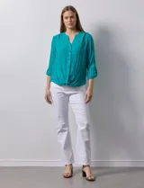 Blusa blanca de gasa marca Zac & Rachel, con cuello a la base, escote en V, abertura central con botones, bolsillo aplicado en el pecho y mangas largas regulables con presilla y botón. Tiene terminación opcional de nudo en el ruedo.