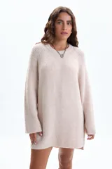 Buzo de tejido de punto en color crudo, con diseño de textura acanalada, cuello redondo, mangas largas holgadas y aberturas laterales en el ruedo.