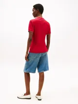 Chomba deportiva de algodón elástico color rojo, con corte slim, escote de pico y ribetes distintivos en blanco y azul marino en el cuello y los puños. Presenta el logo de Tommy Hilfiger bordado en el pecho.