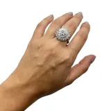 Anillo plateado con forma circular, con incrustaciones de zirconia.