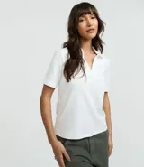 Polo de manga corta color blanco, con cuello abierto tipo V y tejido de suedine de algodón.