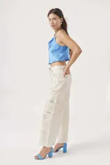 Blusa de satén color crema con escote drapeado y tirantes finos, de corte corto.