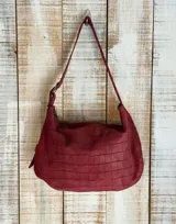 Bolso de hombro tipo hobo con acabado texturizado efecto craquelado en tonos beige y blanco. Cuenta con una correa ajustable con hebilla metálica, cierre superior y diseño espacioso.