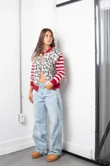 Saco de punto con diseño combinado, presenta un estampado animal print en el cuerpo y mangas con rayas horizontales en rojo y beige. Posee cuello redondo, cierre frontal con botones y terminaciones en tejido acanalado rojo.