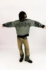 Sweater reversible de tejido de punto con diseño gráfico estilo tribal. Un lado presenta base negra con detalles en gris, mientras que el otro lado presenta base gris con detalles en negro. Posee cuello redondo, mangas largas y puños acanalados.