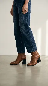 Bota de caña media confeccionada en cuero negro, con diseño de líneas simples, punta cuadrada y taco cuadrado firme.
