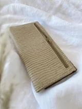 Billetera de cuero con diseño tricolor en tonos turquesa, blanco y beige, con textura tipo reptil. Cuenta con una solapa frontal con cierre de broche y una etiqueta de cuero con el logo grabado.