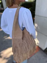 Cartera tipo hobo de cuero color beige con flecos en dos niveles.