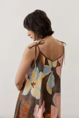Vestido midi de tirantes ajustables con lazo en los hombros, escote en V y diseño amplio con estampado floral abstracto en tonos marrones, rosados, celestes y amarillos.