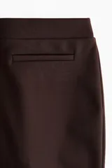 Pantalón de tiro alto confeccionado en punto roma, con diseño ajustado en la parte superior y piernas acampanadas. Presenta bolsillos insertados decorativos en la parte frontal.