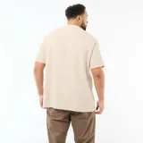 Camiseta de manga corta y cuello redondo en tejido jacquard de algodón color beige, con pequeño estampado tipográfico en el pecho.