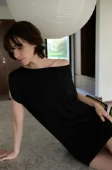 Vestido corto negro con escote bote y diseño de manga corta caída, confeccionado en tela suave y fluida.