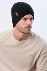 Gorro tejido de punto acanalado en color azul marino, con vuelta y etiqueta decorativa de cuero sintético en el lateral.