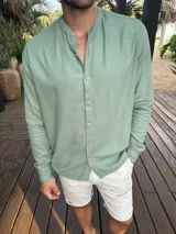 Camisa de lino con cuello mao y cierre frontal de botones de madera. Presenta mangas largas con puños abotonados y un corte recto.