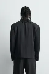 Blazer de corte relajado confeccionada en tejido con mezcla de lana. Presenta cuello con solapas de muesca, cierre frontal de tres botones, bolsillos con solapa en la cadera y un bolsillo en el pecho. Cuenta con manga larga con puños abotonados y aberturas en la espalda.