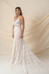 Vestido de novia largo de encaje color marfil con fondo de tul color nude, escote en V y cola de encaje con terminación de blonda.