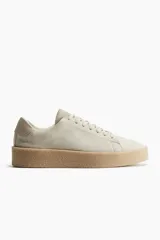 Zapatillas deportivas color crema de gamuza, con collarín acolchado, lengüeta y cierre de cordones. Forro y plantillas en lona de algodón. Suelas texturizadas con diseño.