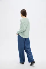 Sweater de tejido de punto fino en color blanco, con cuello redondo a la base y mangas largas de corte holgado.