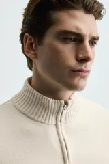 Chaqueta regular fit de punto color beige con cuello perkins, manga larga y cierre frontal con cremallera.