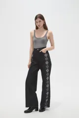Pantalon de jean negro de corte ancho y tiro alto, con estampado de rombos en los laterales de las piernas.