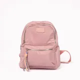 Mochila rosa de tela con cierre superior y bolsillo frontal con cierre. Tiene correas ajustables y un llavero decorativo.