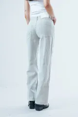 Pantalón de jean corte wide leg, color beige con estampado de rayas verticales finas. Presenta tiro alto, cierre frontal con botón y bolsillos laterales.