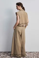 Pantalon de pierna ancha y tiro alto color marron, con bordado en contraste que recorre el ruedo y detalles en calado.