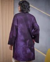 Tapado de lana merino afieltrada color violeta con teñido artesanal Tie Dye en forma de luna. Tiene cierre cruzado asimétrico con broches, cuello alto y bolsillos laterales.