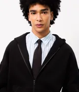 Campera con capucha de felpa negra, con cierre frontal, bolsillos canguro y estampa tipográfica gótica en color blanco en las mangas.