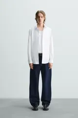 Camisa de corte slim fit con textura, cuello italiano y manga larga con puños abotonados. Presenta cierre frontal con botones.