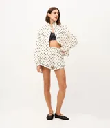 Bermuda runner deportiva de microfibra color blanco con estampado de lunares negros, tiro medio, cintura elástica y detalles de ribetes en contraste.