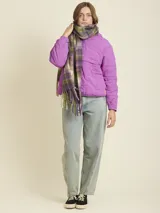 Bufanda de tejido suave con diseño a cuadros en tonos beige y amarillo neón. Presenta flecos en los extremos y una etiqueta de la marca Rusty.